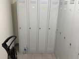 plusieurs casiers dans le couloir d'un immeuble, avec un balai et une serpillière