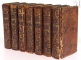 six vieux livres sont alignés sur une surface blanche