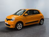 La petite voiture orange est garée dans une grande pièce.