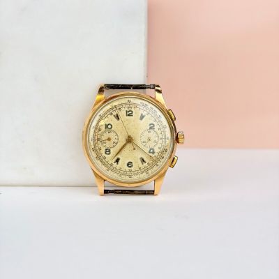 une image montrant un gros plan d'une montre en or posée sur une surface en marbre