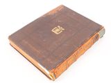 an old brown book sitting on top of a white surface