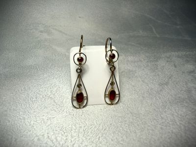 a pair of earrings with garnets on them sitting on a white surface