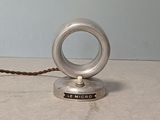 un petit objet en argent posé sur une table, avec une corde