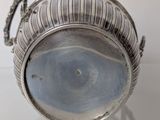a silver bowl with a handle on a table