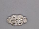 un gros plan d'une broche sertie de diamants sur un fond gris