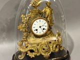 a gold clock under a glass dome on a table