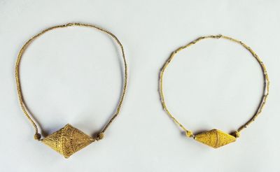 two gold hoops with small beads on them on a white surface
