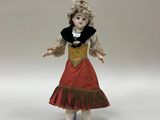 porcelain doll of a young girl in a red dress with a black collar