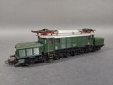 a green train on the tracks on a gray surface
