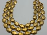 un collier en or orné de trois rangées de feuilles sur fond blanc