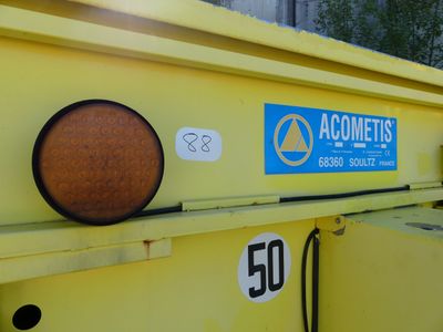 un camion-benne jaune sur lequel est accrochée une pancarte