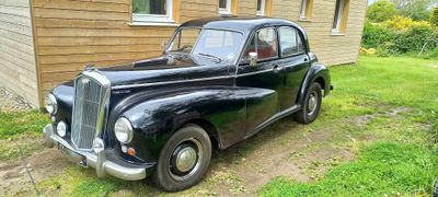 une vieille voiture noire garée devant une maison