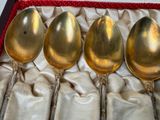 four gold spoons in a box with a red lining
