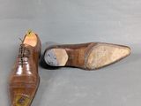 pair of men ' s brown leather shoes on a grey background