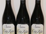 three bottles of red wine sit on a white table