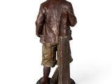 bronze statue of a man standing on a rock with a suitcase
