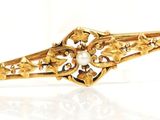 une image montrant un gros plan d'une broche en or posée sur une surface blanche