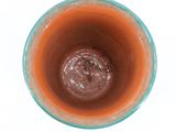 a brown substance in a blue cup on a white surface
