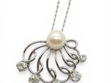 a close up of a pearl and diamond pendant on a chain