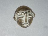 an image of a small bronze mask on a white surface