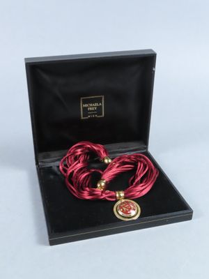 une photo d'un collier et d'un bracelet rouges dans un coffret noir