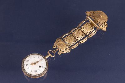 une horloge dorée entourée d'une chaîne, posée sur un fond bleu