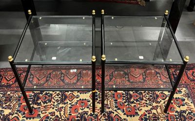 une paire de tables basses en verre et en laiton posées sur un tapis