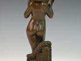 bronze statue of a woman sitting on a box with a bird in her hand