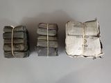 three stacks of newspapers are wrapped in twine and tied with twine