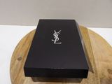 a black box with a white monogram on it sitting on a wooden board