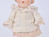 a small doll that is standing on a white surface