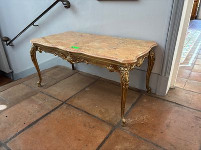 une petite table avec un plateau en marbre posée sur un sol carrelé