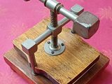 un petit objet métallique posé sur un socle en bois, sur une surface rose