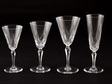 four empty wine glasses are lined up on a black surface