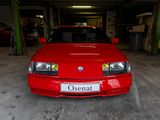 une voiture rouge garée dans un garage, avec une plaque d'immatriculation
