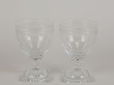 two clear wine glasses sitting on top of each other on a white surface