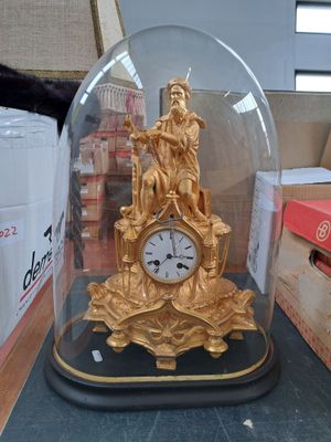 une horloge en or sous un dôme de verre sur une table