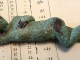 une figurine en bronze représentant un bébé allongé sur une feuille de papier