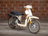 a white motor bike parked in front of a brick wall