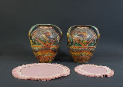 two vases and a coaster on a table with a black background