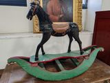 un cheval à bascule en bois posé sur une table devant un tableau