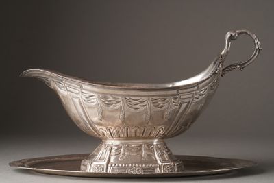 a silver gravy on a silver plate on a gray surface