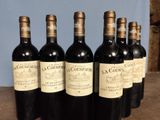 six bottles of wine are lined up on a wooden table