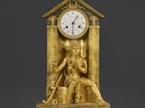 une horloge en or sur laquelle est représentée la statue d'une femme