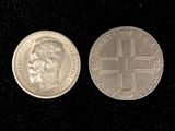 two silver coins with a cross on them on a black surface