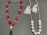 two necklaces with pearls and a tassel on a table