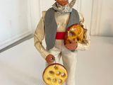 figurine of a man with a hat holding a bagel and a pretzel