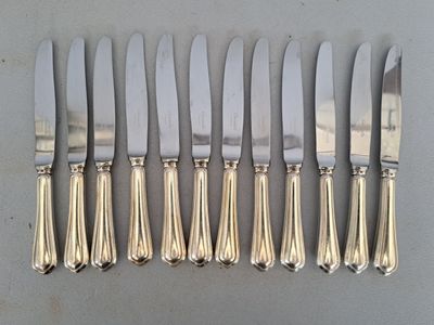 six silverplated knives and six knives on a table