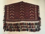 a large red and brown rug with tassels hanging on the wall