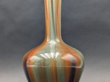 a vase that is sitting on a table in front of a gray background